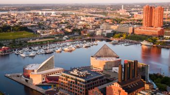 Inner Harbor waterfront of Baltimore, MD, in sunrise. Yachts moored at piers. Downtown District aerial view