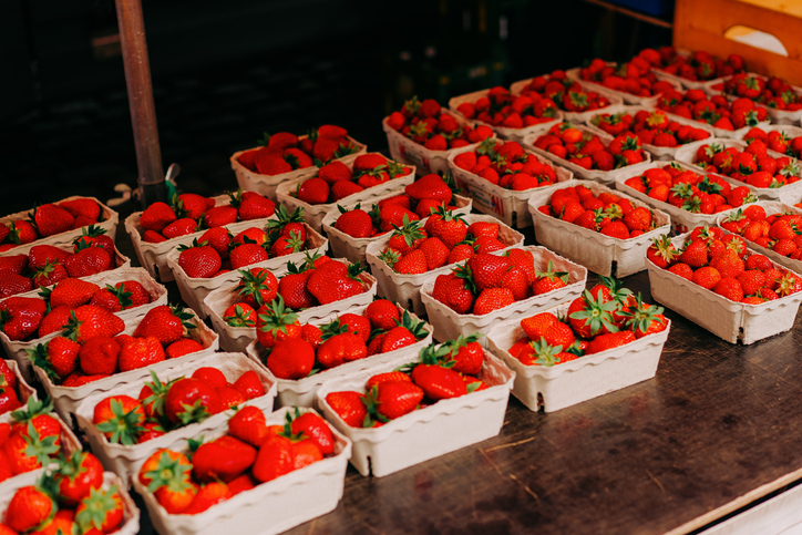 Strawberries displayed in market stall. Many boxes with fresh and juicy berries on farm market