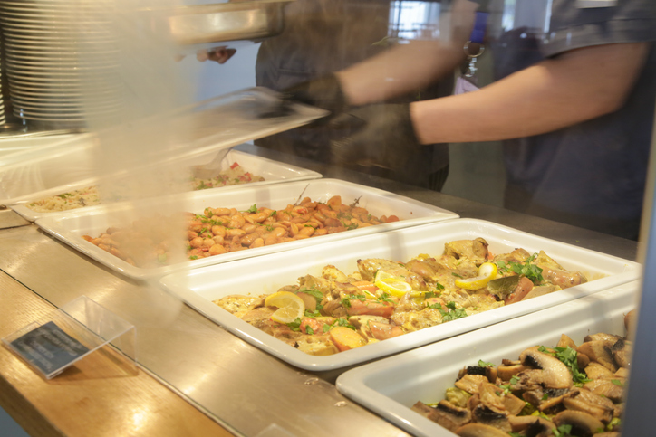 Buffet style service - Canteen worker at serving line putting food on the plate