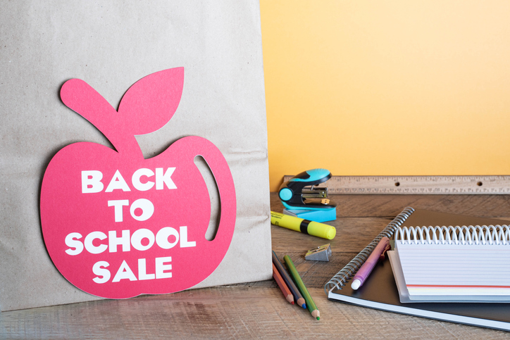 Back to school, apple shaped tag, on paper, shopping bag. Yellow background.