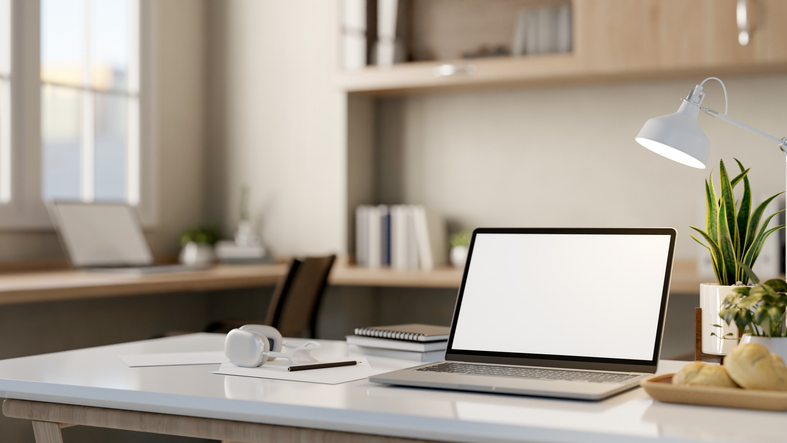 A close-up image of a laptop computer mockup on a white table in a modern comfortable office.