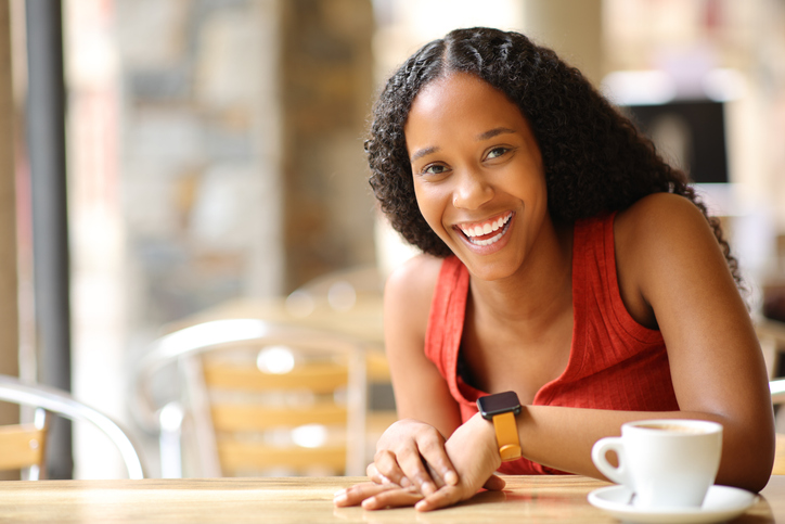 Happy black woman laughing looking at camera in a bar
