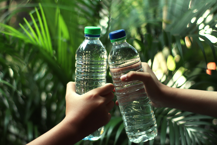 Hands holding bottles of water.