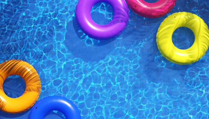 Multi-colored swimming rings in swimming pool. Pool party, summer background. Top view