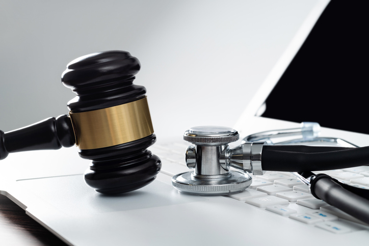 Gavel and stethoscope on laptop keyboard