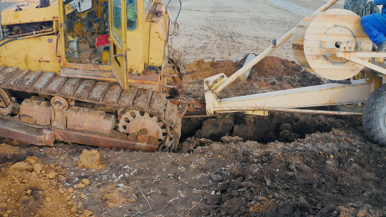 Bulldozer laying cable in trench for infrastructure development