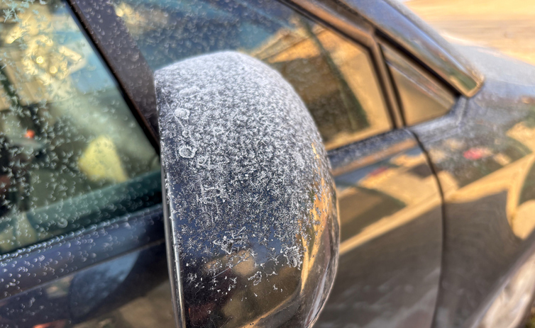 Frozen car side mirror covered in heavy frost