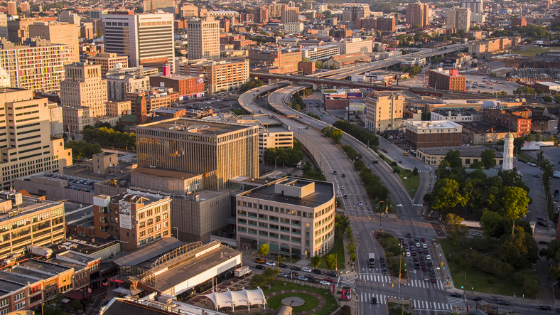 Sunny urban cityscape line the highway. Downtown connection with suburban areas of big city. Road leading to the distance at dawn in Baltimore, Maryland. Aerial view
