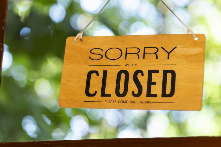 Sorry we are closed sign hanging on door with green bokeh background, business closure concept