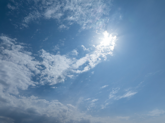 Bright Blue Sky with Scattered Clouds and Shining Sun