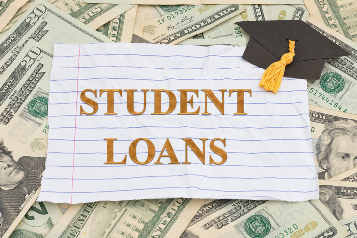 Student Loans on lined paper with twenty dollar bill cash with grad cap