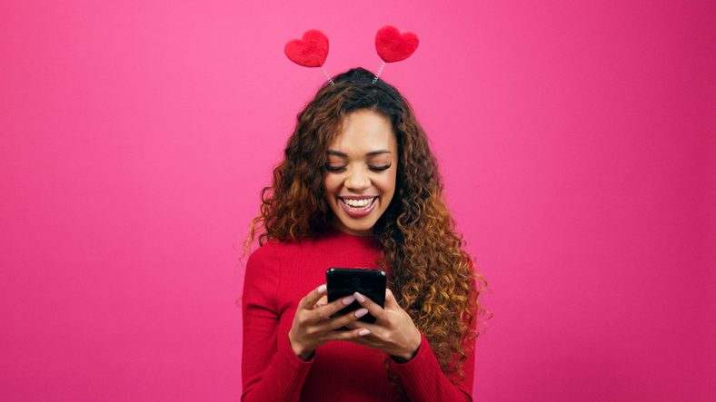 Beautiful young woman texts and smiles, Valentines Day, dating app
