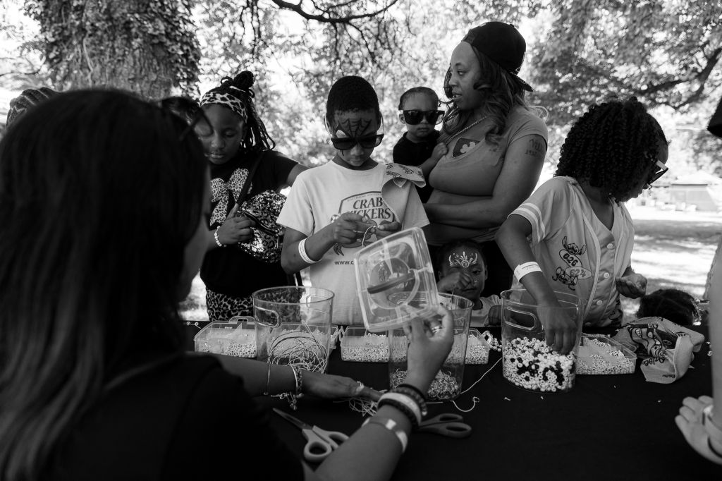 A group of people, including children, gathered around a table displaying various items and reading from a document.