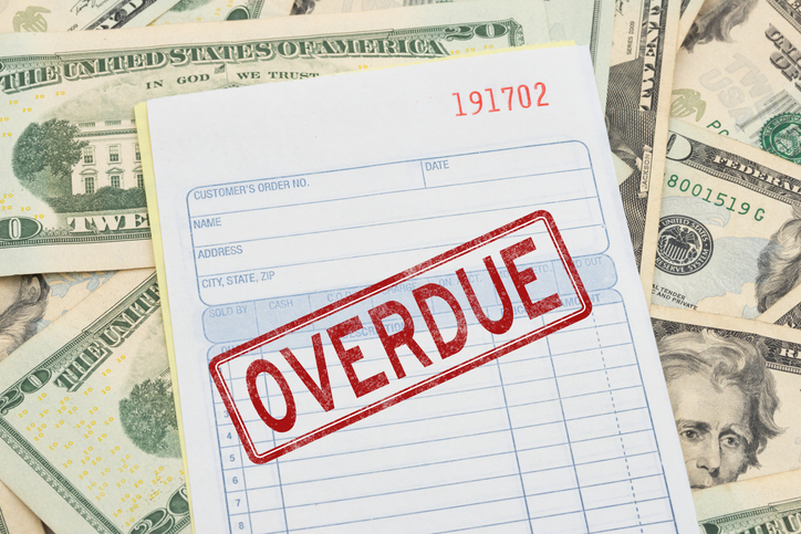 Overdue text red stamp on a invoice on twenty dollar bills for unpaid bills
