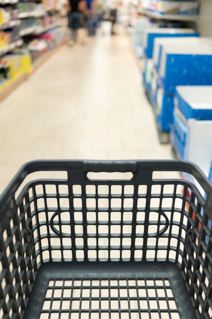 Empty shopping cart moving through grocery store aisle